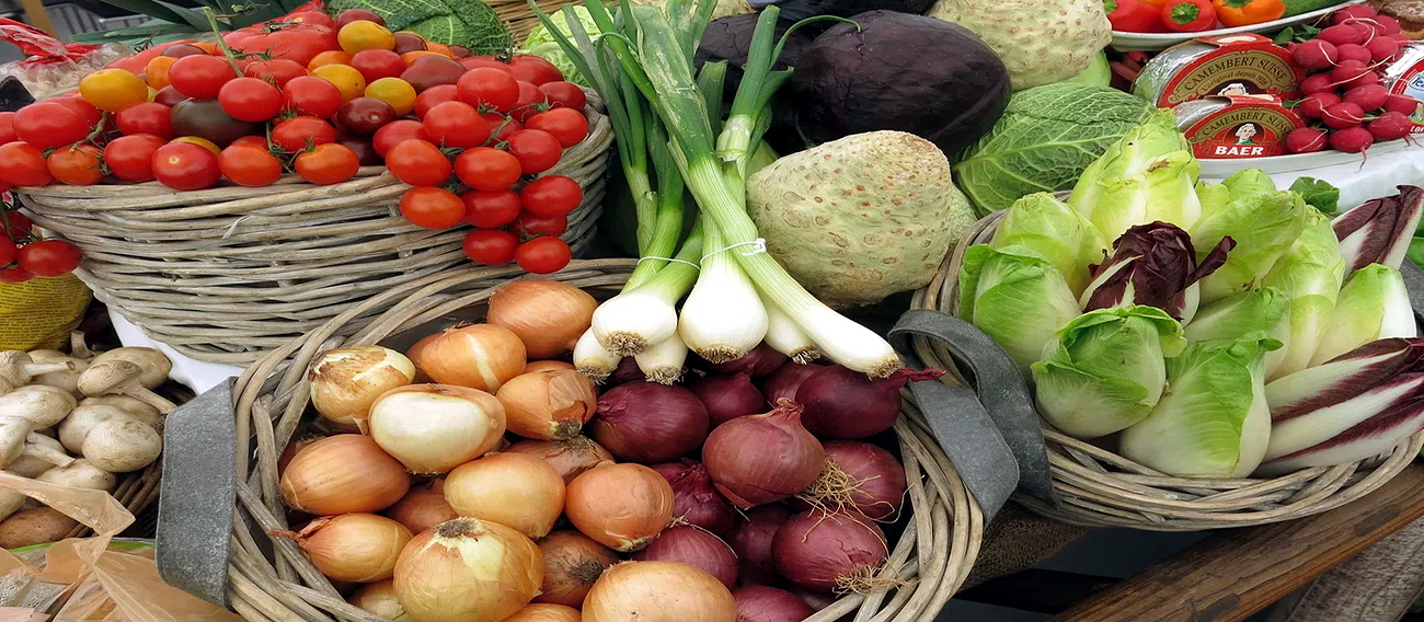 Bundle of fresh tomatoes, white and red onions, garlic, squash, mushrooms, lettuce during Saturday market