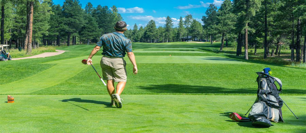 Golfer on tee-box watching his ball after hitting