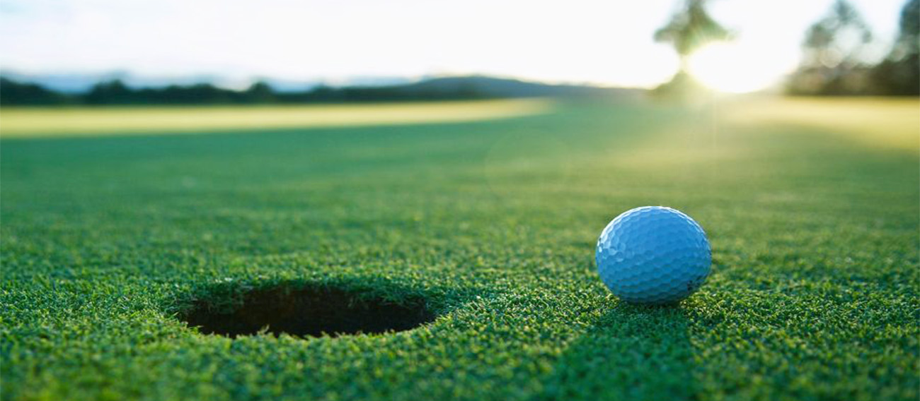 Golfball next to the cup on the green
