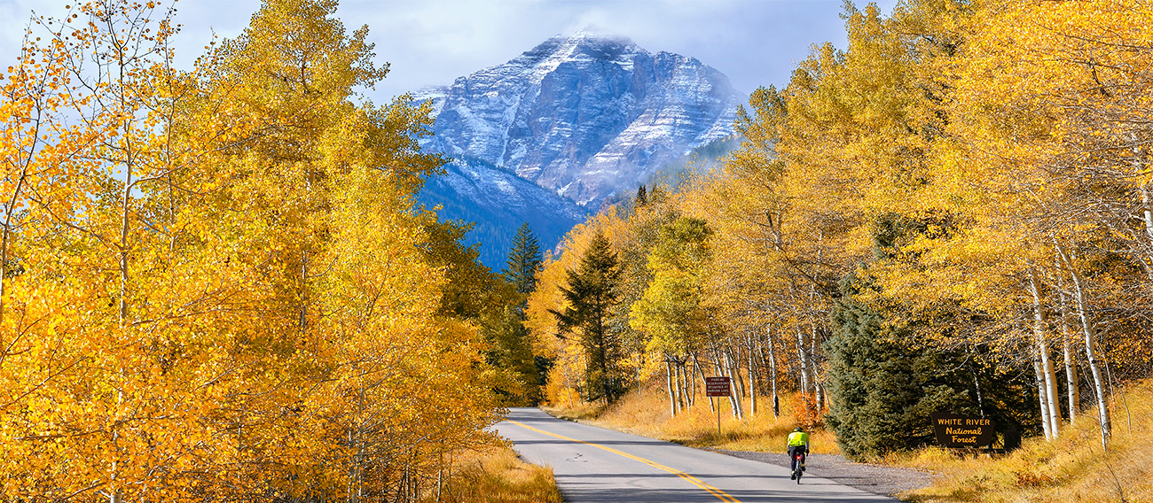 man road biking up road going towards Pyramid Peak near Aspen, Colorado