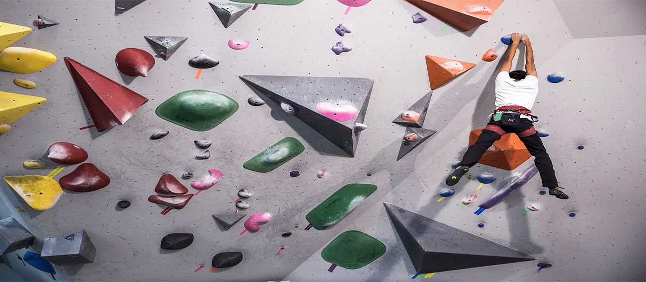 Man hanging from hand holds while Indoor Climbing