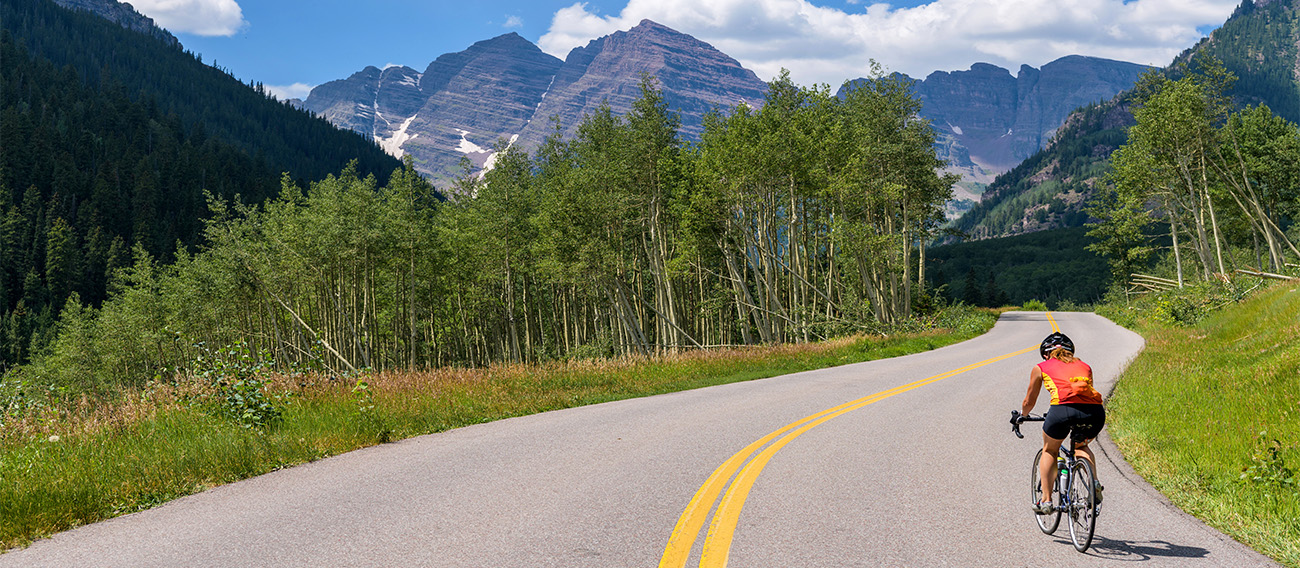 Women riding road bike up to Maroon Bells